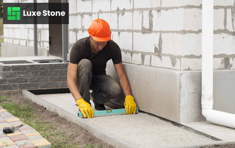 Worker performing foundation maintenance on a house.